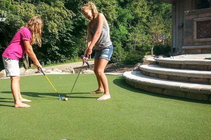 Kids playing golf on backyard putting green from SYNLawn